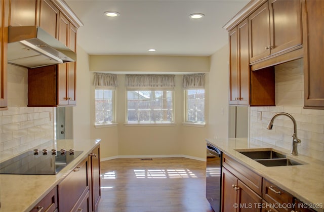 kitchen featuring dishwasher, wood finished floors, black electric stovetop, under cabinet range hood, and a sink