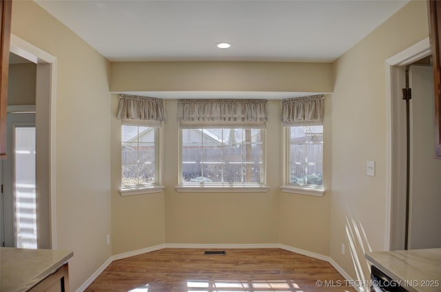 unfurnished dining area with recessed lighting, visible vents, baseboards, and wood finished floors