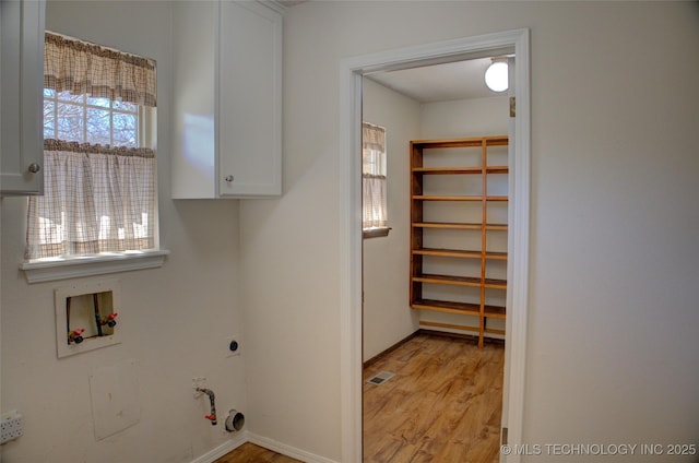 clothes washing area with hookup for a washing machine, hookup for a gas dryer, light wood-style floors, cabinet space, and electric dryer hookup