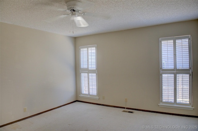 carpeted empty room with baseboards, ceiling fan, visible vents, and a textured ceiling