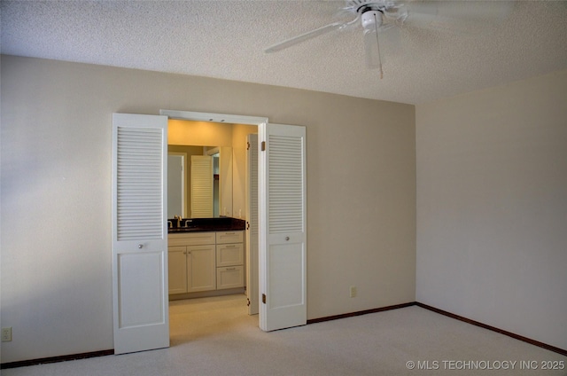 unfurnished bedroom with a textured ceiling, baseboards, and a sink