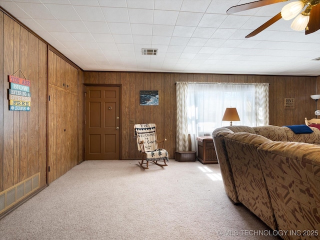 interior space with wooden walls, visible vents, and light carpet