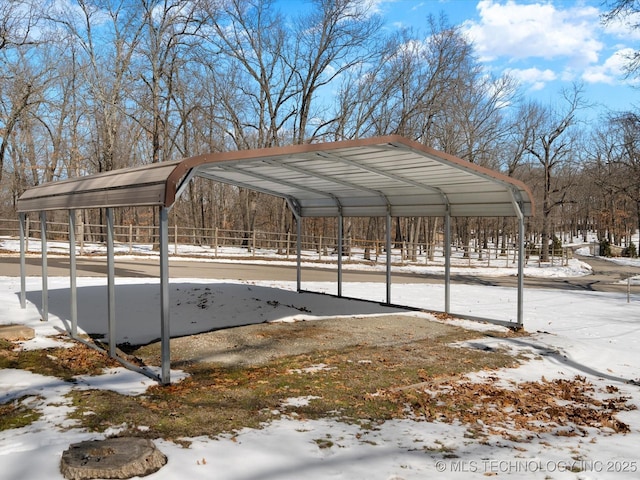 snow covered parking featuring a detached carport