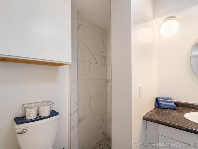 full bathroom with a tile shower, vanity, and toilet