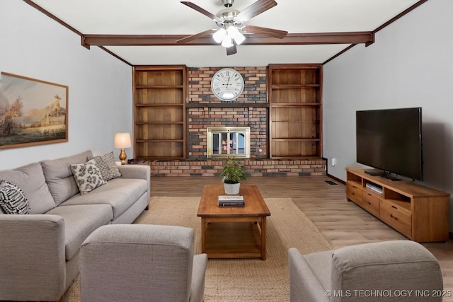 living area with ceiling fan, light wood-style flooring, a fireplace, built in features, and beam ceiling