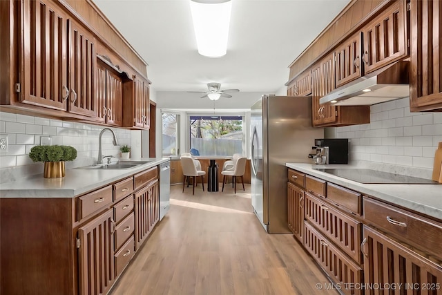 kitchen featuring light countertops, stainless steel appliances, a sink, and under cabinet range hood