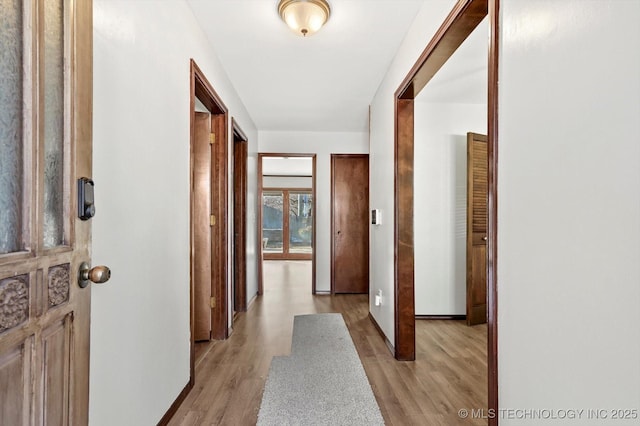 hallway with baseboards and light wood-style floors