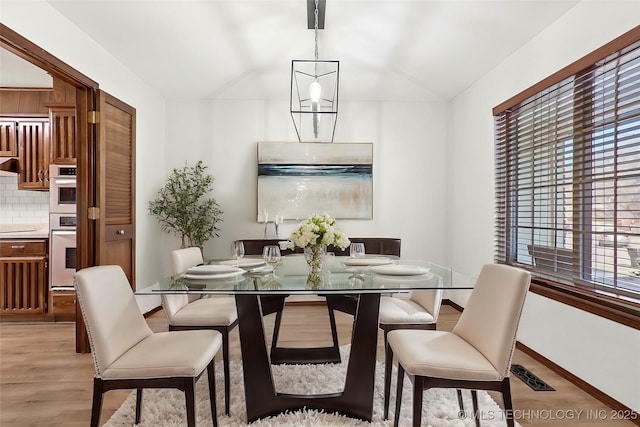 dining space with a notable chandelier, light wood-type flooring, visible vents, and baseboards