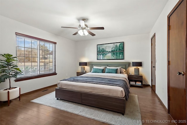 bedroom with baseboards, dark wood finished floors, visible vents, and a ceiling fan