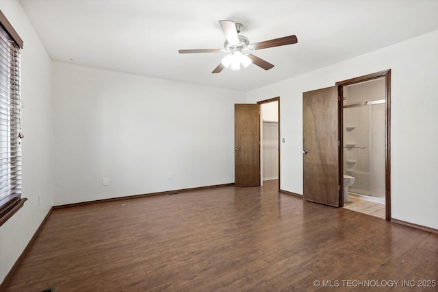 unfurnished bedroom with ensuite bathroom, ceiling fan, dark wood-style flooring, and baseboards