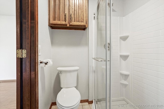 bathroom with a shower stall, toilet, and baseboards