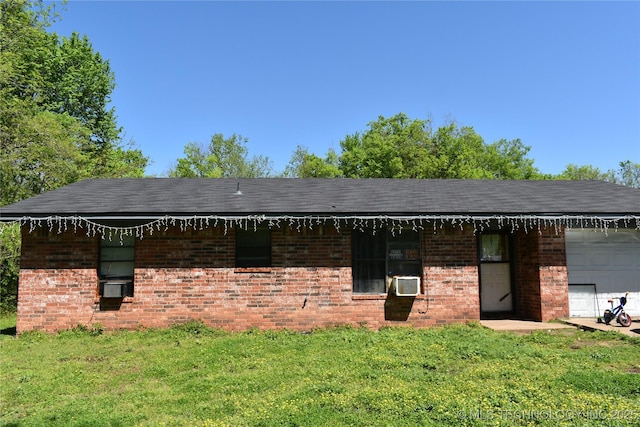 exterior space with a garage, cooling unit, brick siding, and a lawn