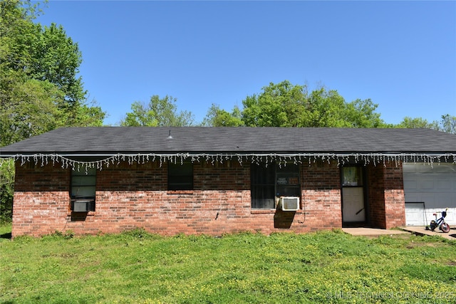 exterior space with a garage, cooling unit, brick siding, and a lawn