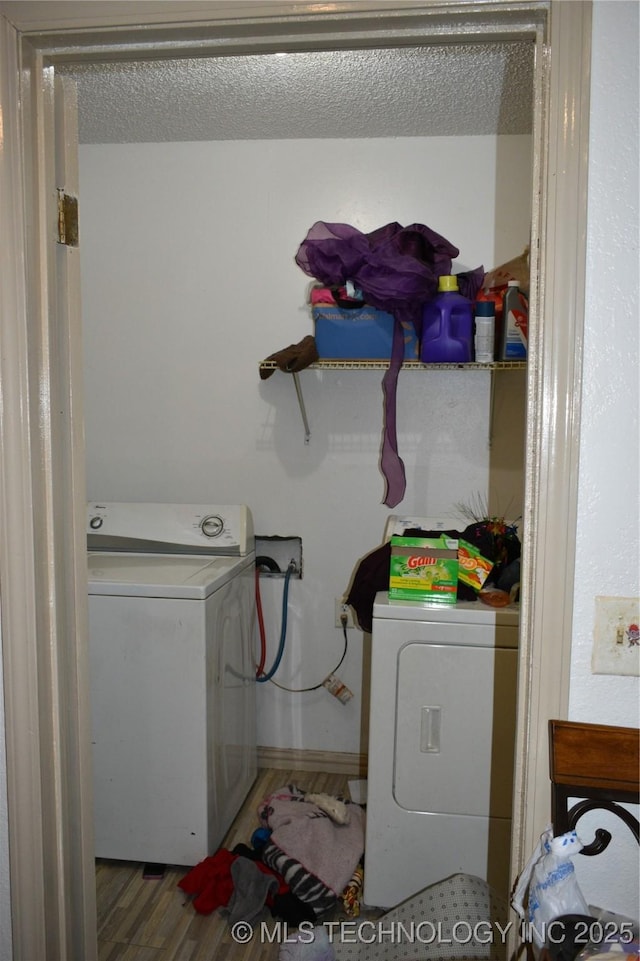 laundry area with washer / dryer, laundry area, a textured ceiling, and wood finished floors