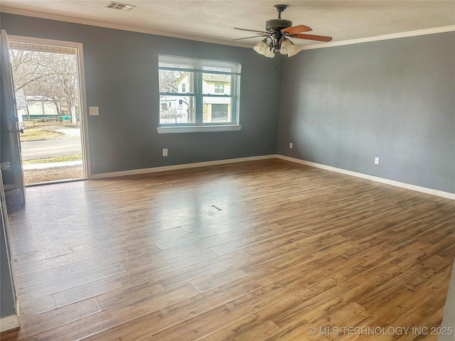 empty room with light wood finished floors, a wealth of natural light, and crown molding