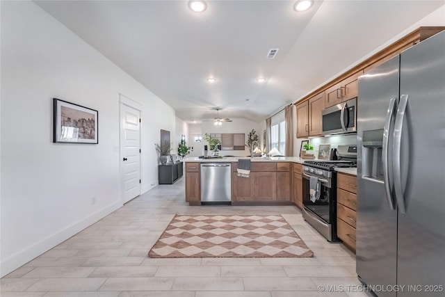 kitchen with visible vents, light countertops, appliances with stainless steel finishes, brown cabinetry, and a peninsula