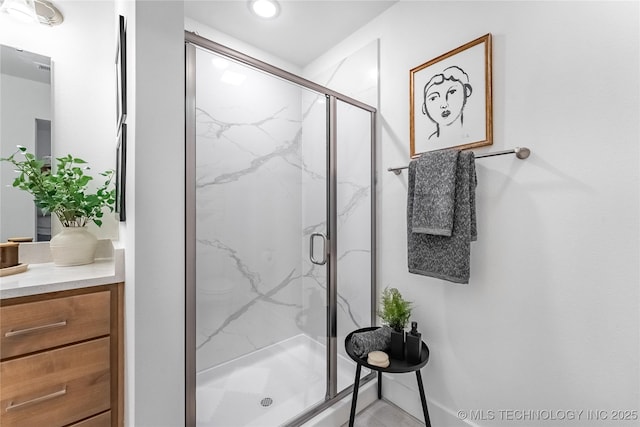 full bathroom featuring a marble finish shower and vanity