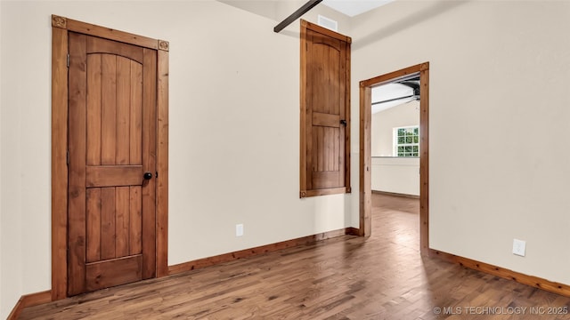 spare room featuring lofted ceiling, wood finished floors, visible vents, and baseboards