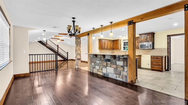 living area with a notable chandelier, baseboards, stairway, light wood-type flooring, and beam ceiling