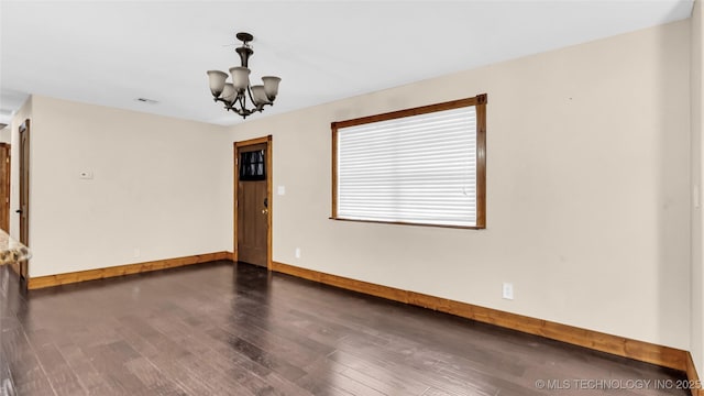 empty room featuring an inviting chandelier, baseboards, visible vents, and dark wood-style floors