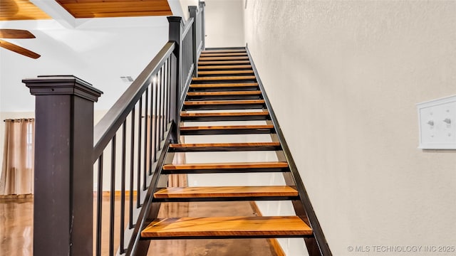 staircase with beam ceiling and ceiling fan