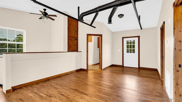 empty room with lofted ceiling, ceiling fan, baseboards, and wood finished floors