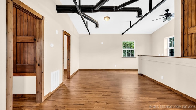 unfurnished room with visible vents, vaulted ceiling, ceiling fan, wood finished floors, and baseboards