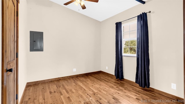 empty room with electric panel, baseboards, a ceiling fan, light wood-style flooring, and vaulted ceiling