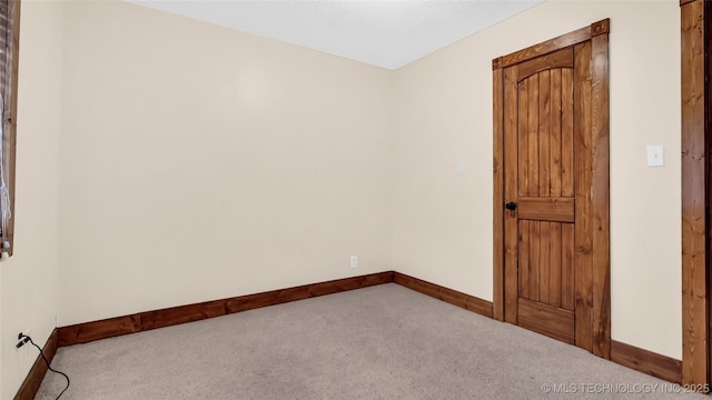 unfurnished room featuring light carpet and baseboards