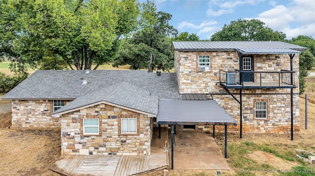 view of front of property featuring stone siding, metal roof, and a balcony