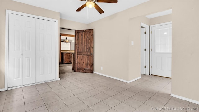 unfurnished bedroom with a closet, ceiling fan, baseboards, and light tile patterned floors