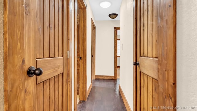 corridor with baseboards and dark wood-type flooring