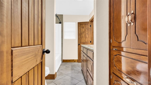 bathroom with baseboards, toilet, tile patterned floors, vanity, and shower / bathing tub combination