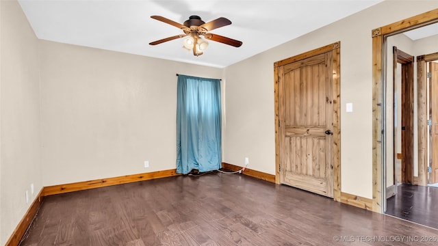 empty room featuring a ceiling fan, dark wood-style flooring, and baseboards