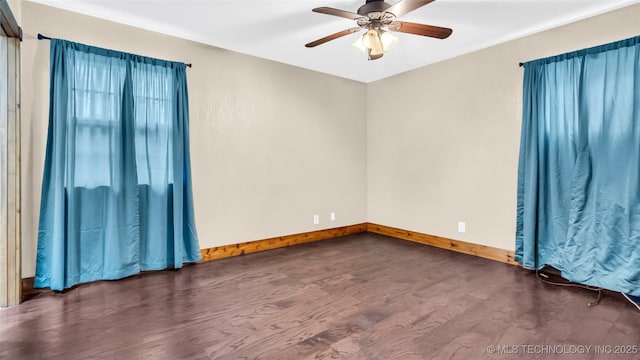 unfurnished room with baseboards, dark wood finished floors, and a ceiling fan