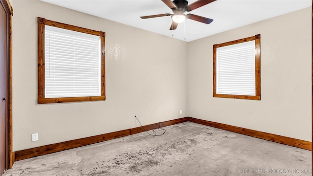 unfurnished room featuring plenty of natural light, ceiling fan, unfinished concrete flooring, and baseboards