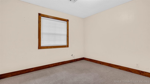 empty room featuring light carpet, visible vents, and baseboards