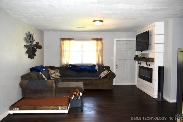 living room featuring dark wood-style flooring, visible vents, and baseboards