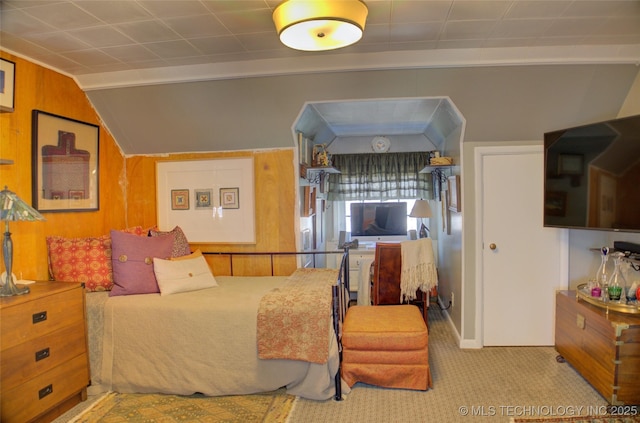 bedroom with lofted ceiling, carpet flooring, and wooden walls