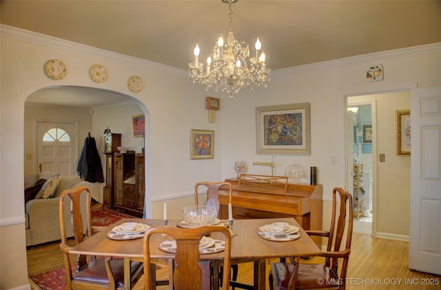 dining area featuring light wood-style floors, arched walkways, crown molding, and baseboards