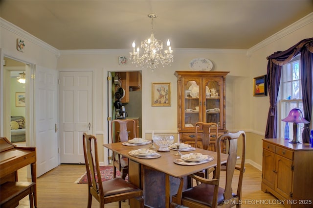 dining space with ceiling fan with notable chandelier, light wood-type flooring, and crown molding