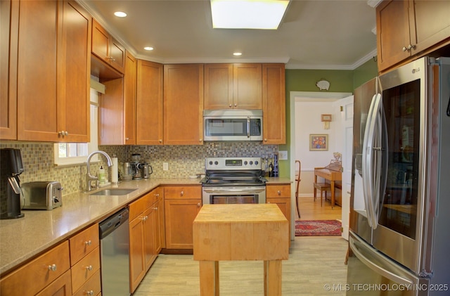 kitchen with stainless steel appliances, tasteful backsplash, light wood-style flooring, ornamental molding, and a sink