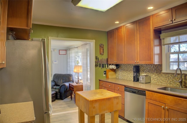 kitchen with a sink, light countertops, appliances with stainless steel finishes, backsplash, and brown cabinets