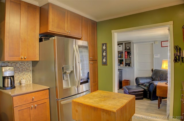 kitchen featuring wooden counters, ornamental molding, light wood-type flooring, decorative backsplash, and stainless steel fridge