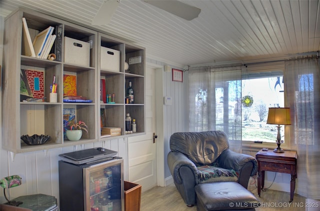 living area featuring a healthy amount of sunlight, light wood finished floors, wine cooler, and wooden ceiling