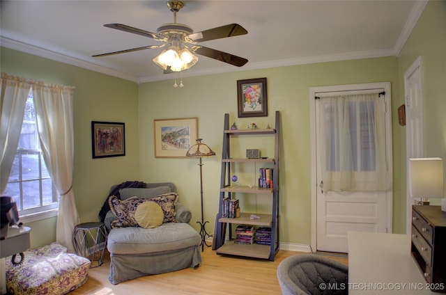 sitting room with baseboards, wood finished floors, a ceiling fan, and crown molding