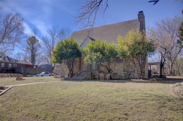 view of front of property with roof with shingles, a chimney, fence, stone siding, and a front lawn