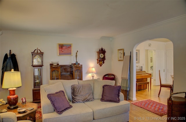 living room with light wood finished floors, arched walkways, and crown molding