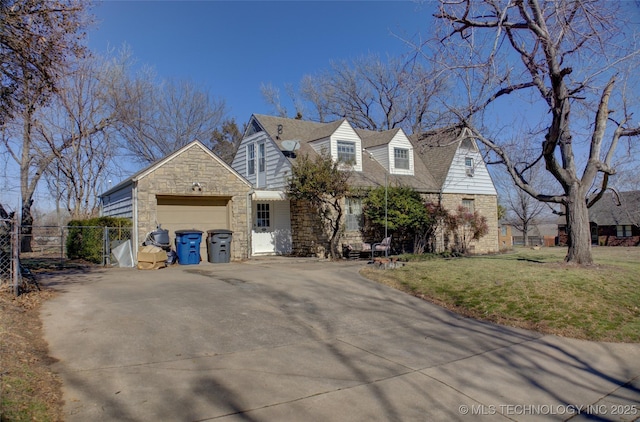 cape cod house featuring an attached garage, fence, stone siding, driveway, and a front lawn