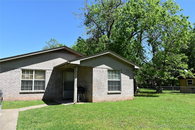 view of front facade with a front lawn, fence, and brick siding